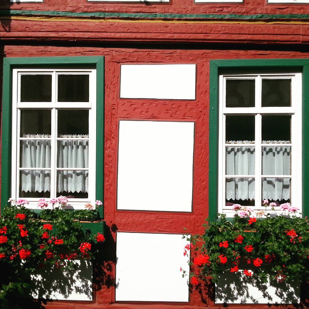 Zwei Fenster, 
zwei Blumenkästen, 
zwei Gardinen,
ein Fachwerkhaus